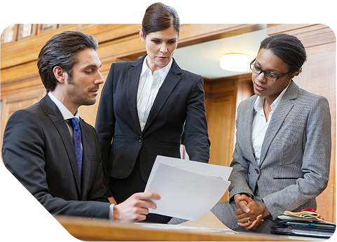 Three lawyers reviewing a document in a courtroom
